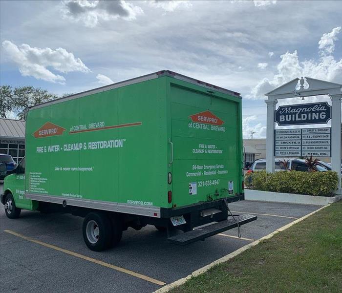 Green SERVPRO box truck sitting in the parking lot of a strip mall