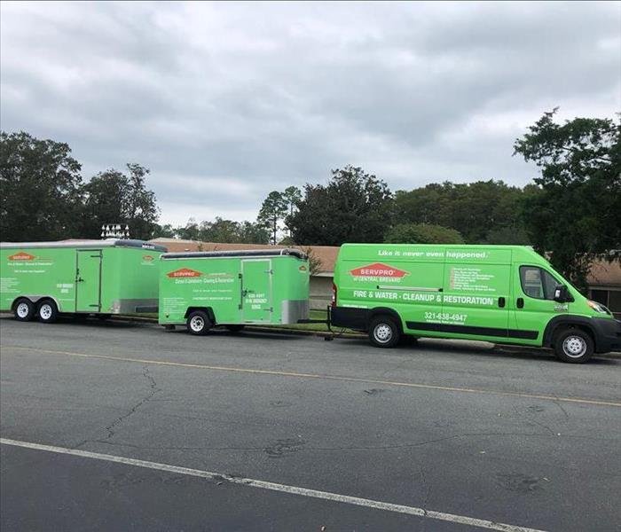 A SERVPRO vehicle with two trailers parked on the road. 